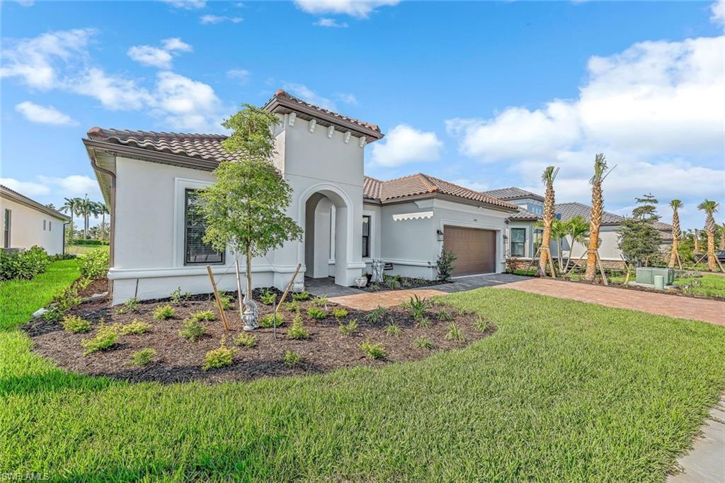Mediterranean / spanish-style home featuring a garage, driveway, a front lawn, and a tile roof