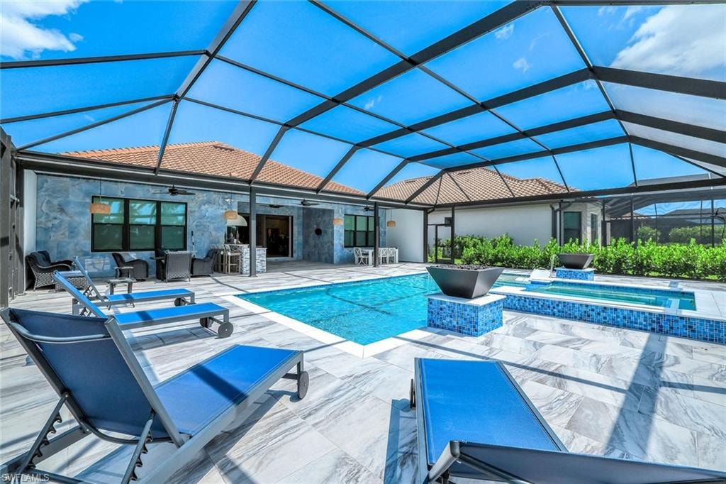 View of pool with ceiling fan, a patio, a pool with connected hot tub, an outdoor living space, and glass enclosure