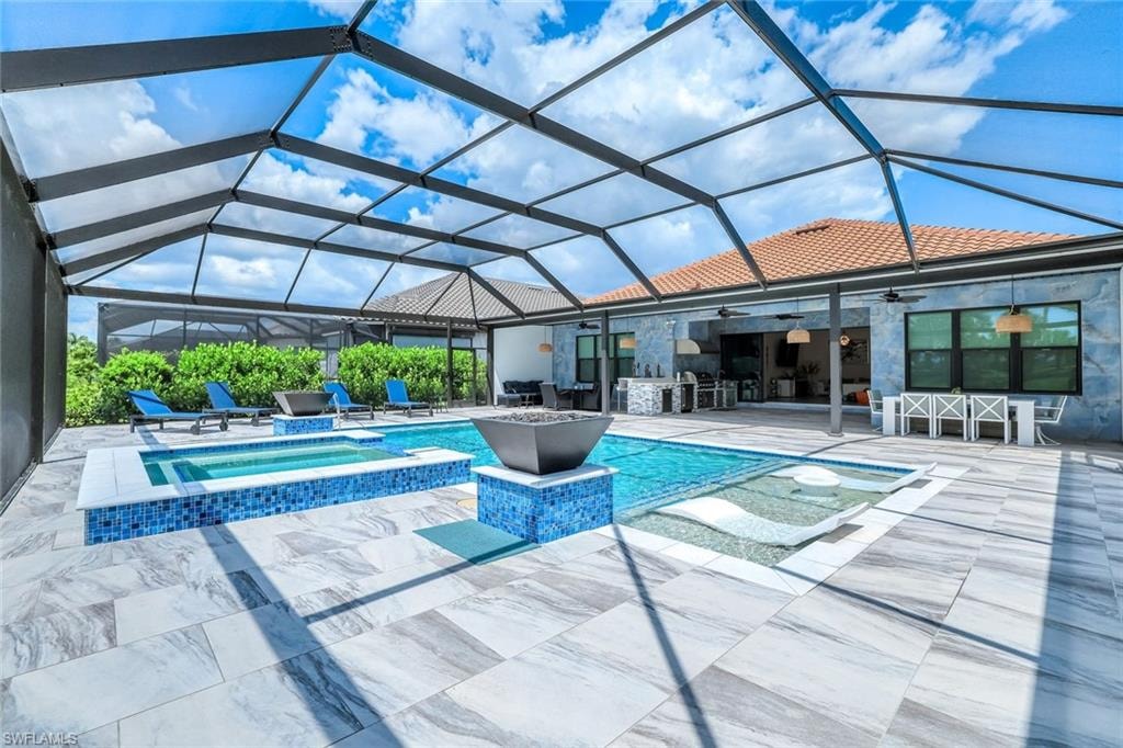 View of pool featuring ceiling fan, a patio area, a pool with connected hot tub, and a lanai