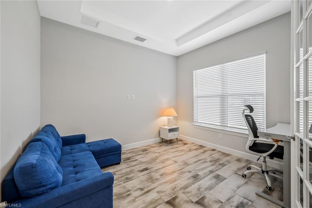 Office space with wood finished floors and a raised ceiling