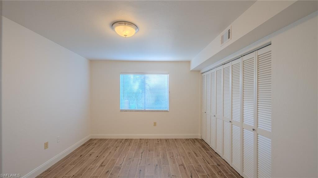 Unfurnished bedroom with wood finish floors and a closet