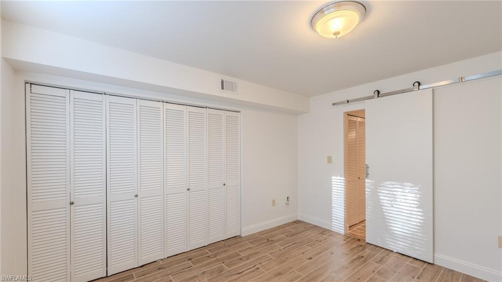 Unfurnished bedroom featuring wood tiled floors and a barn door