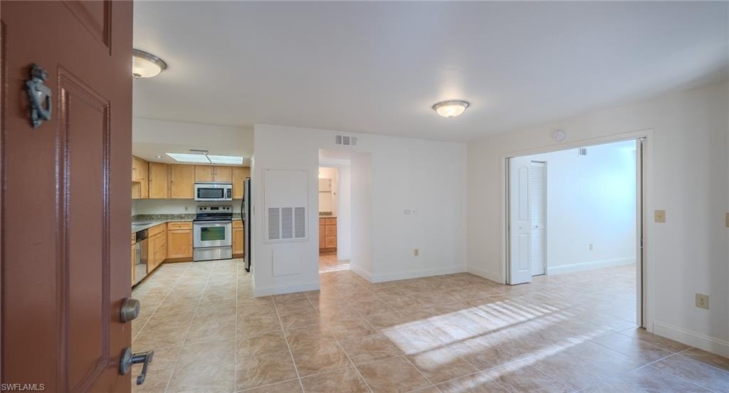 Kitchen with stainless steel appliances, light tile patterned floors, and light countertops