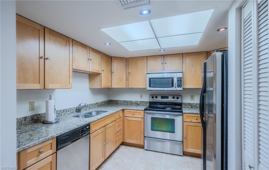 Kitchen with stainless steel appliances, light stone countertops, light tile patterned floors, recessed lighting, and light wood finish cabinetry