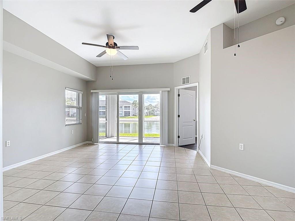 Empty room with a ceiling fan, a water view, and light tile patterned flooring
