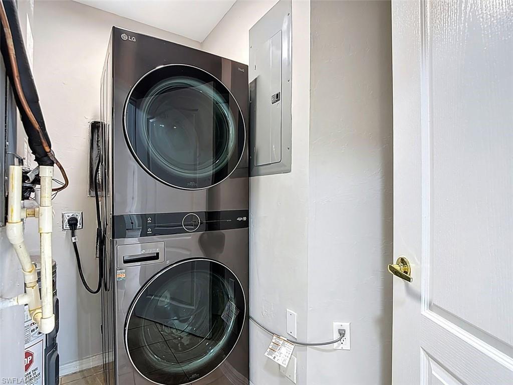 Laundry room with stacked washer and clothes dryer and electric panel