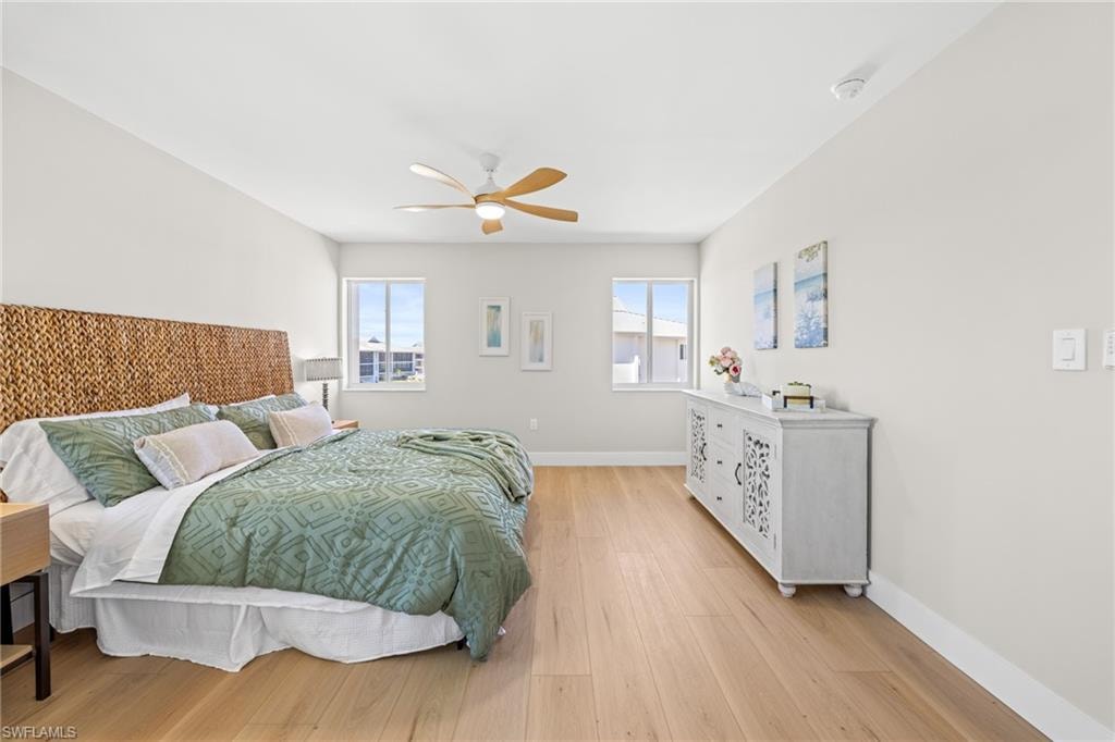 Bedroom with light wood-style flooring, multiple windows, and ceiling fan