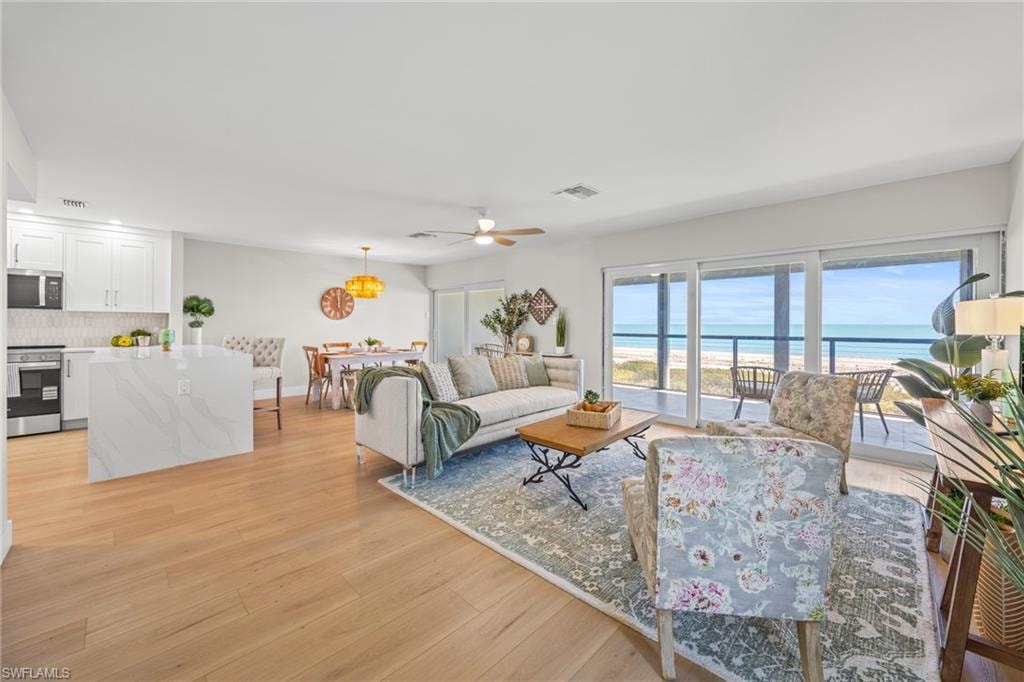 Living area with a water view, light wood-type flooring, and a ceiling fan