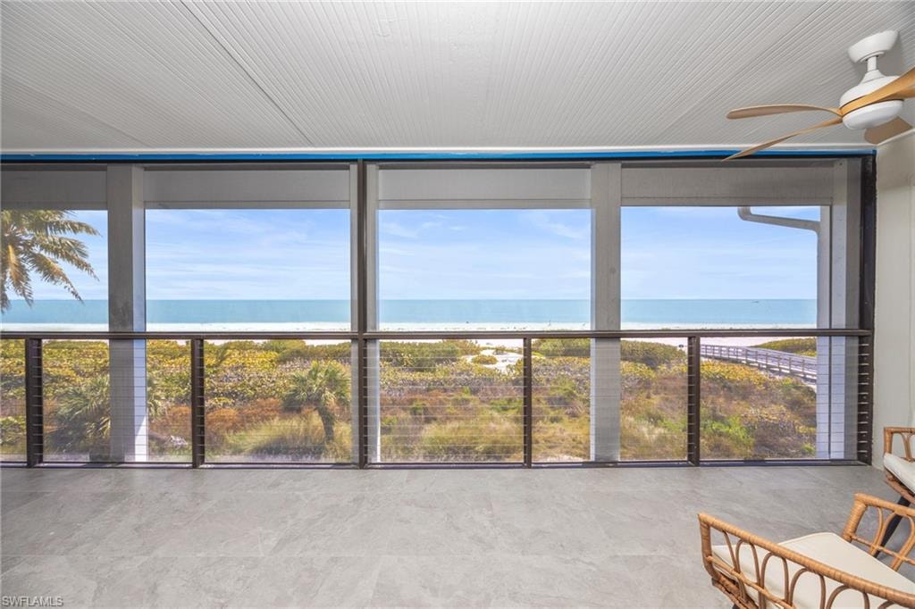 Sunroom / solarium featuring view of water and beach