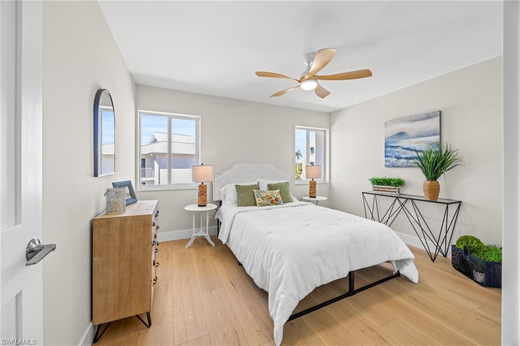 Bedroom featuring light wood-type flooring, multiple windows, and ceiling fan