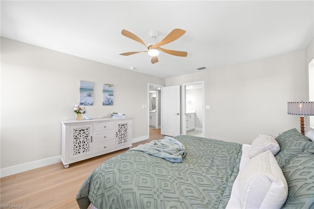 Bedroom with light wood finished floors, ceiling fan, and ensuite bath