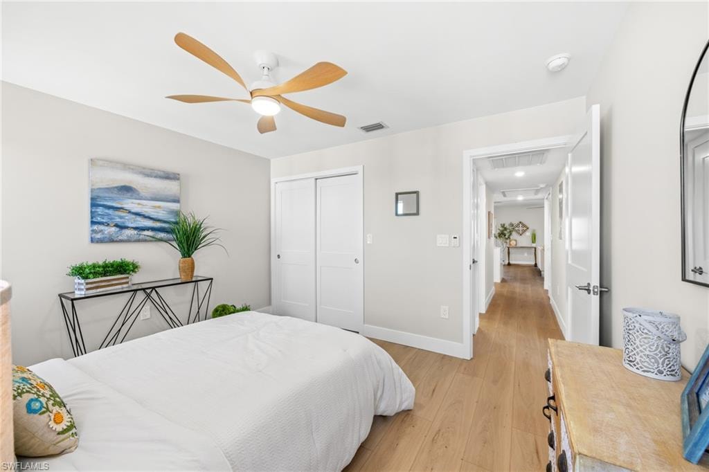Bedroom with light wood-style floors, ceiling fan, and a closet
