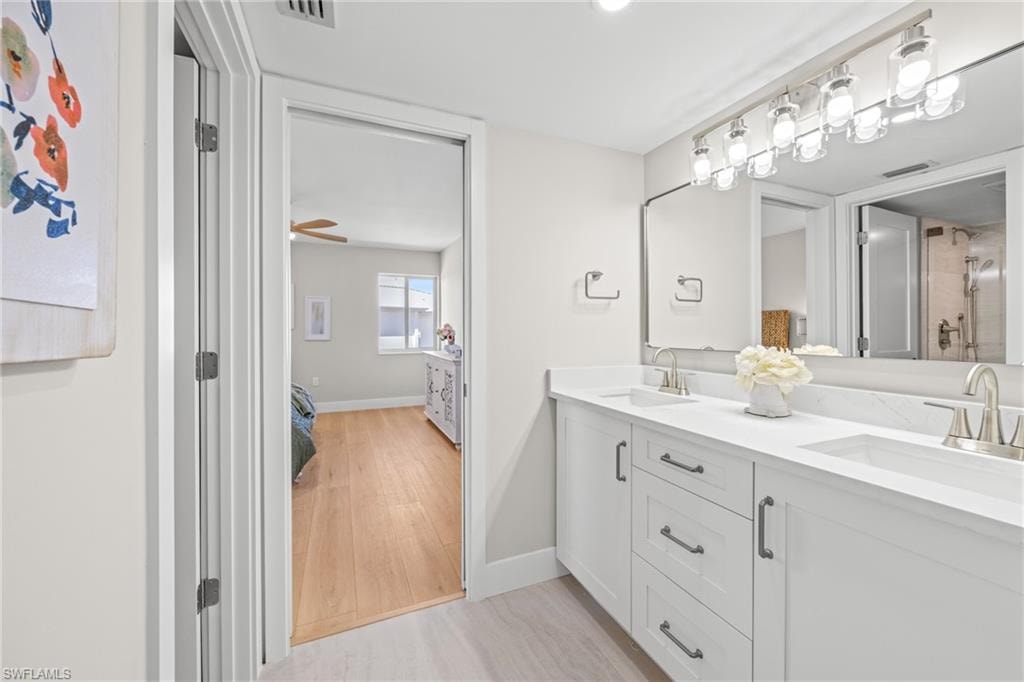 Bathroom with double vanity, light wood-type flooring, connected bathroom, and a shower