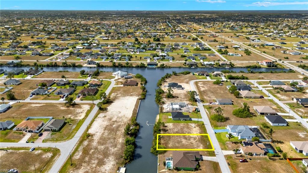 Aerial perspective of suburban area with property boundaries highlighted and a nearby body of water