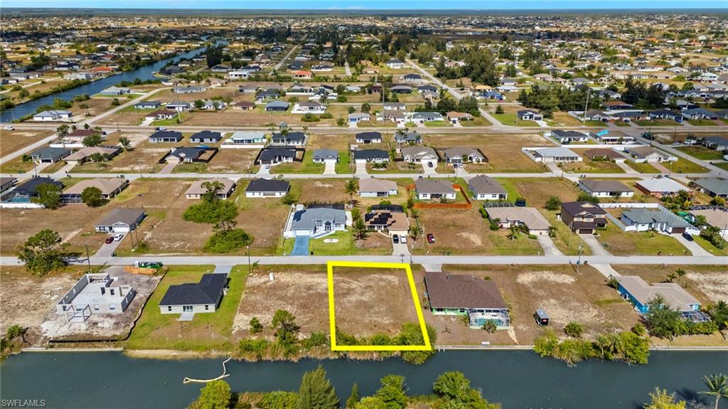Aerial view of residential area featuring a nearby body of water and property parcel outlined