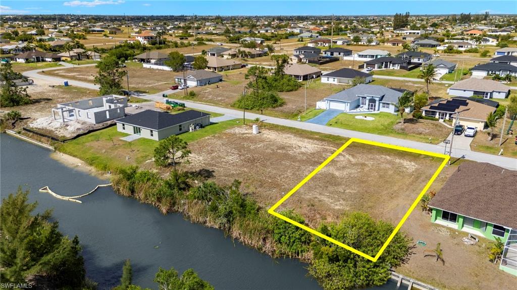Aerial view of residential area with property parcel outlined and a nearby body of water