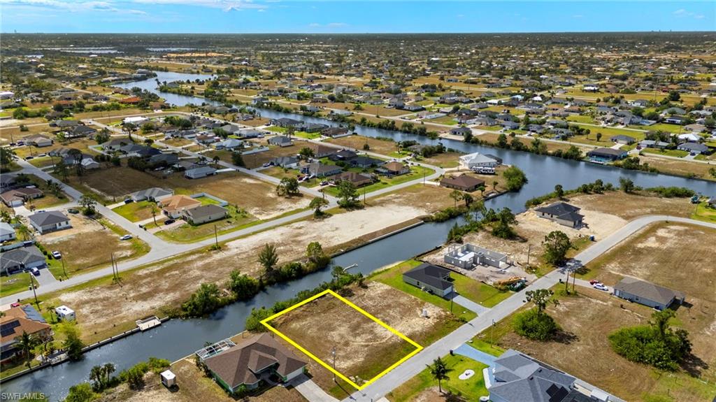 Aerial perspective of suburban area featuring a nearby body of water and property boundaries highlighted