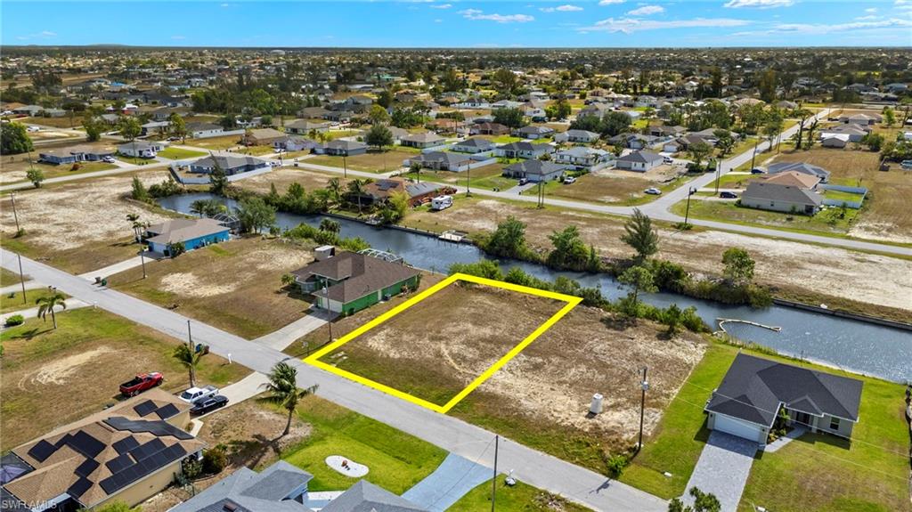 Aerial view of residential area with property boundaries highlighted and a nearby body of water