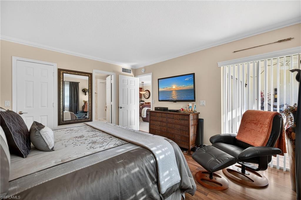Bedroom featuring crown molding, wood finished floors, and access to exterior