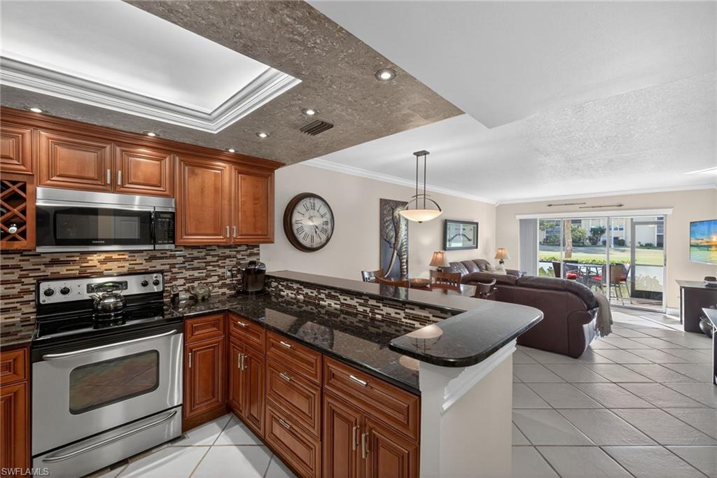 Kitchen with stainless steel appliances, ornamental molding, tasteful backsplash, dark stone counters, and wood finish cabinets