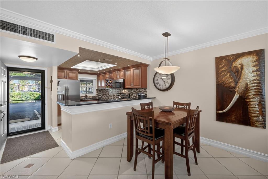 Dining room featuring crown molding, a tray ceiling, and light tile patterned flooring