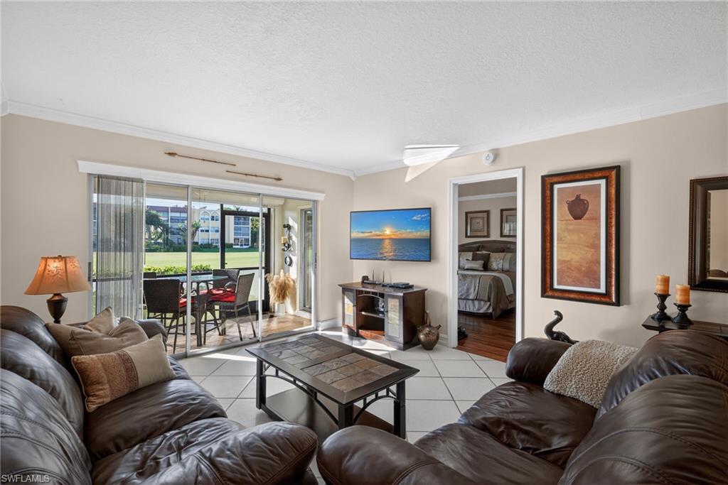 Living area featuring crown molding, light tile patterned floors, and a textured ceiling