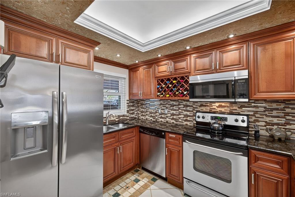 Kitchen featuring ornamental molding, stainless steel appliances, dark stone counters, and wood finish cabinets