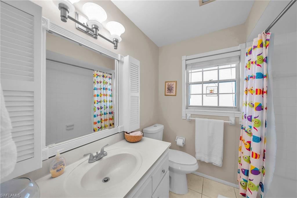 Full bathroom featuring vanity, a shower with curtain, and light tile patterned floors