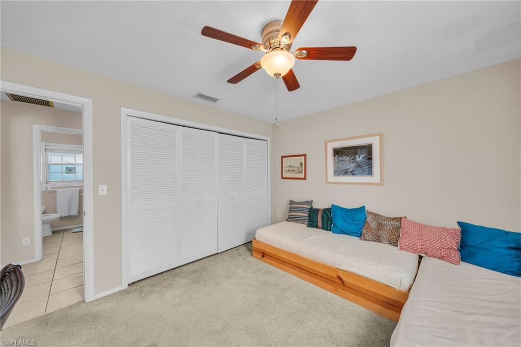Bedroom with a closet, light colored carpet, and ceiling fan