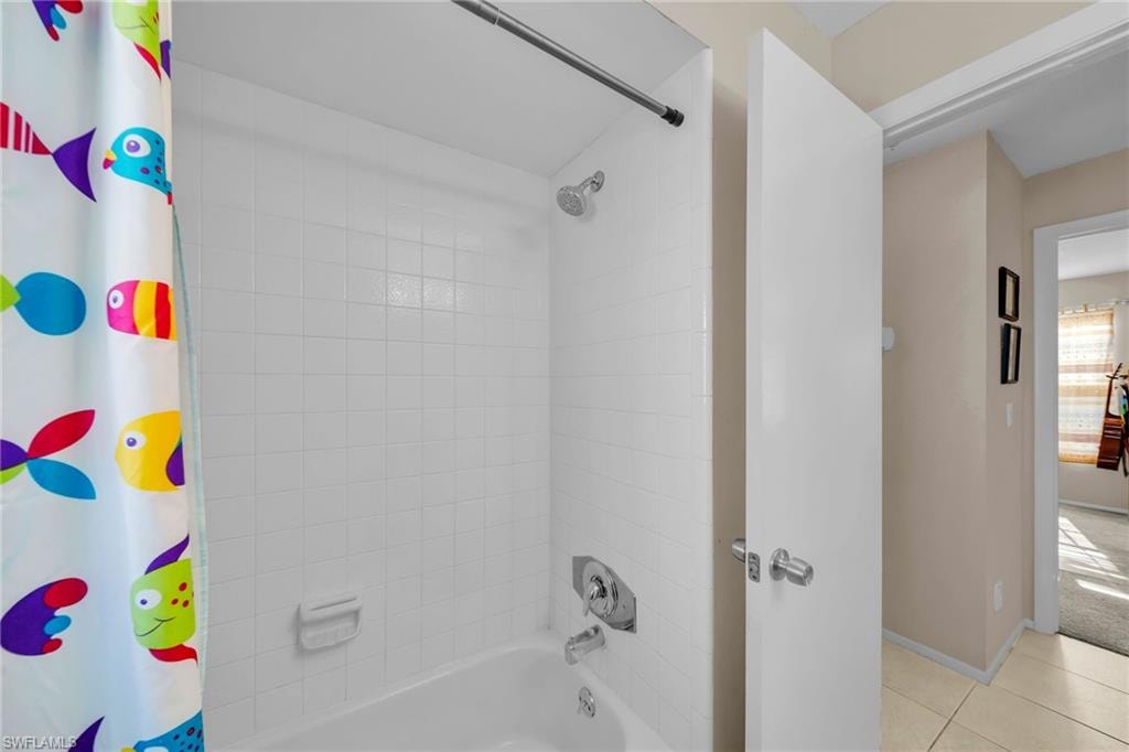 Bathroom featuring shower / bath combo with shower curtain and light tile patterned floors
