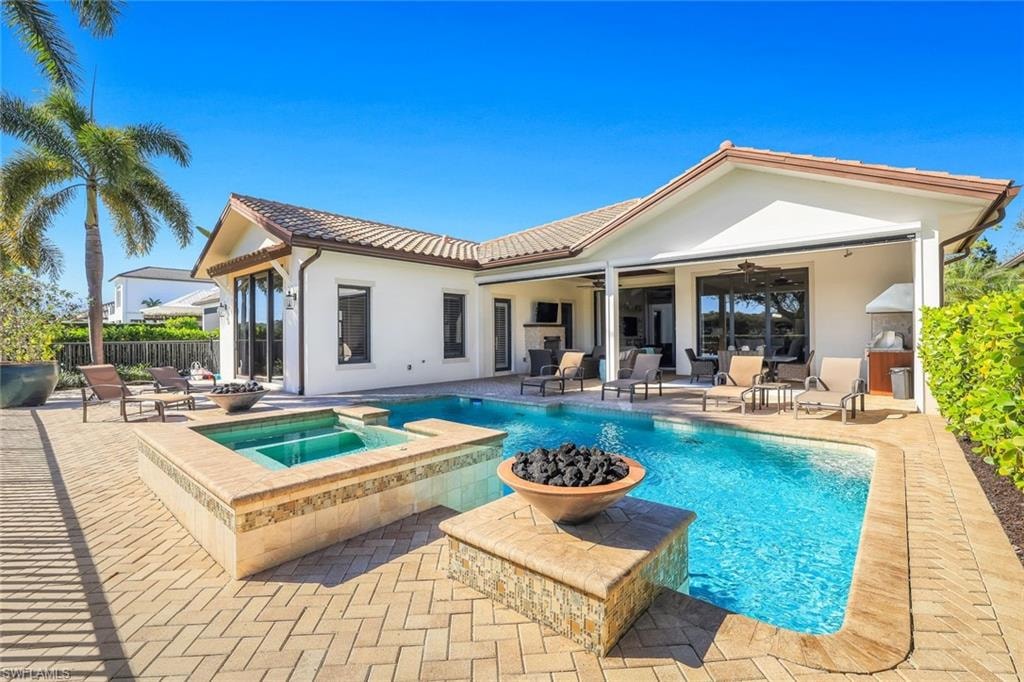 Back of property with ceiling fan, a patio, stucco siding, a pool with connected hot tub, and a tile roof