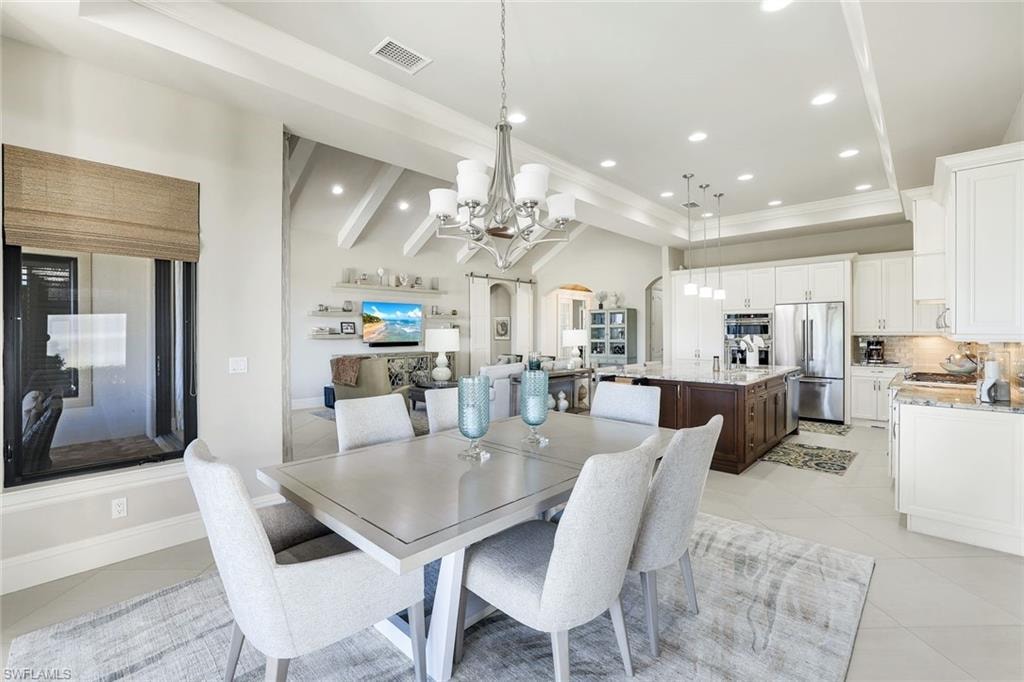 Dining area with light tile patterned flooring, hanging lights, arched walkways, and vaulted ceiling with beams