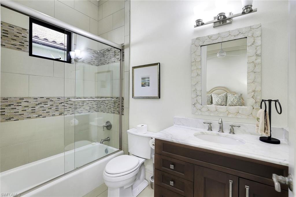 Bathroom with vanity and bath / shower combo with glass door