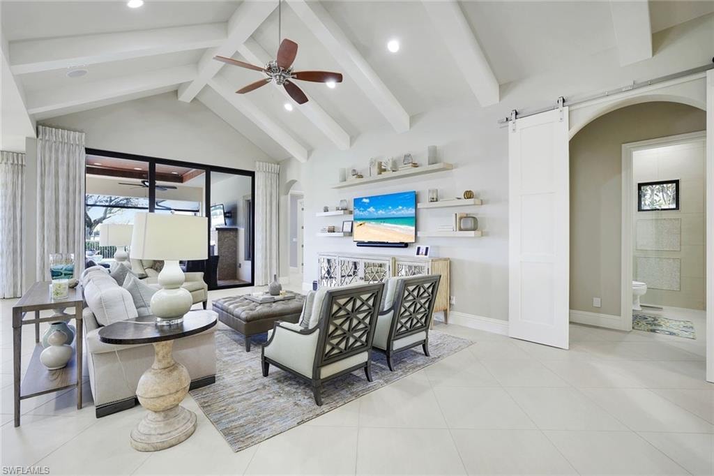 Living room with arched walkways, a barn door, ceiling fan, recessed lighting, and light tile patterned floors
