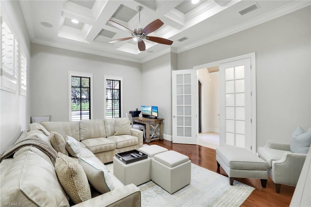 Living area featuring crown molding, coffered ceiling, a ceiling fan, wood finished floors, and french doors