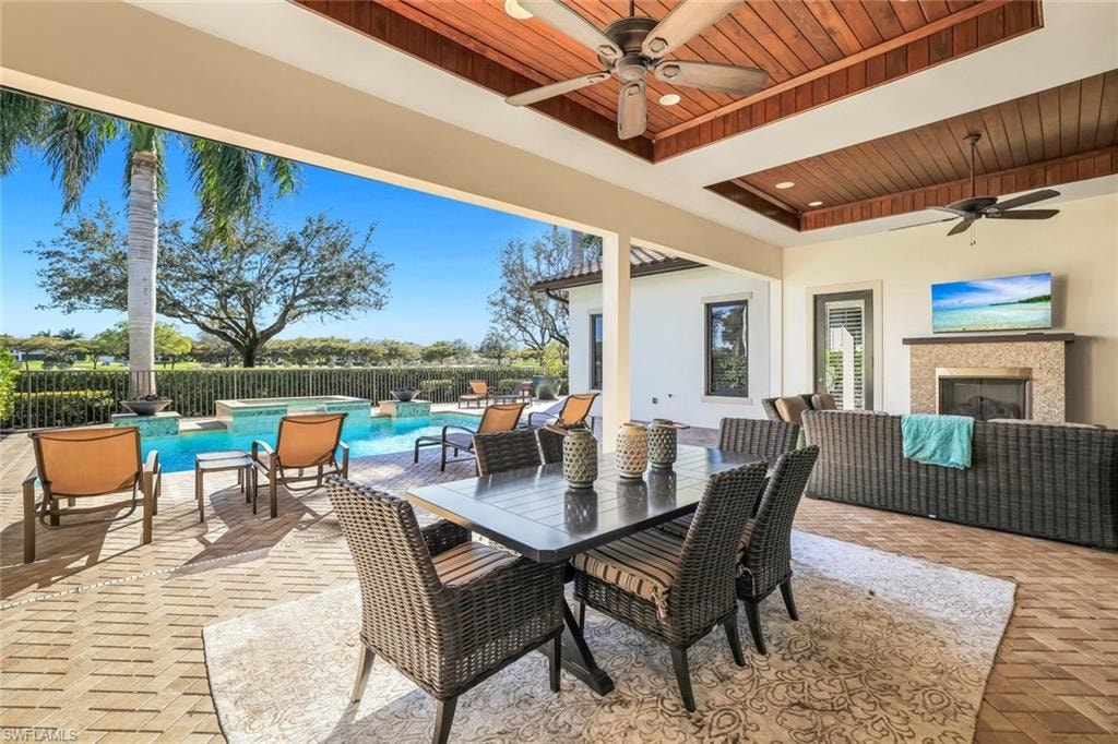 Fenced backyard featuring a ceiling fan, a patio, a pool with connected hot tub, and an outdoor living / dining area
