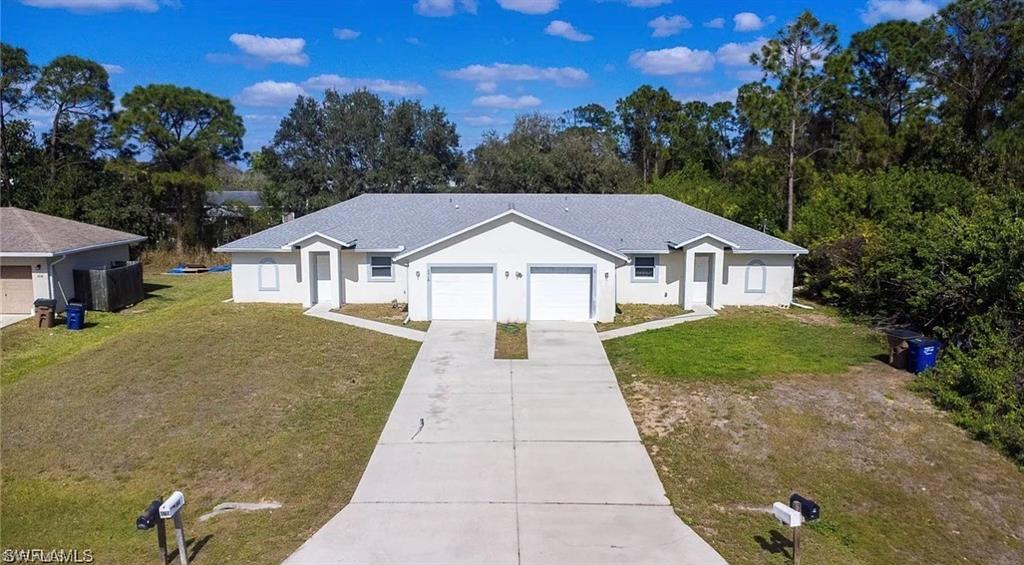 Ranch-style house with a front lawn, stucco siding, driveway, an attached garage, and roof with shingles