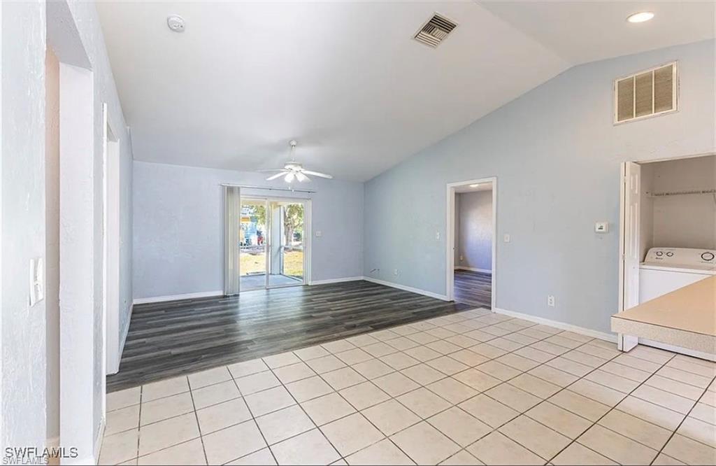 Spare room with lofted ceiling, ceiling fan, light tile patterned floors, and washer / dryer