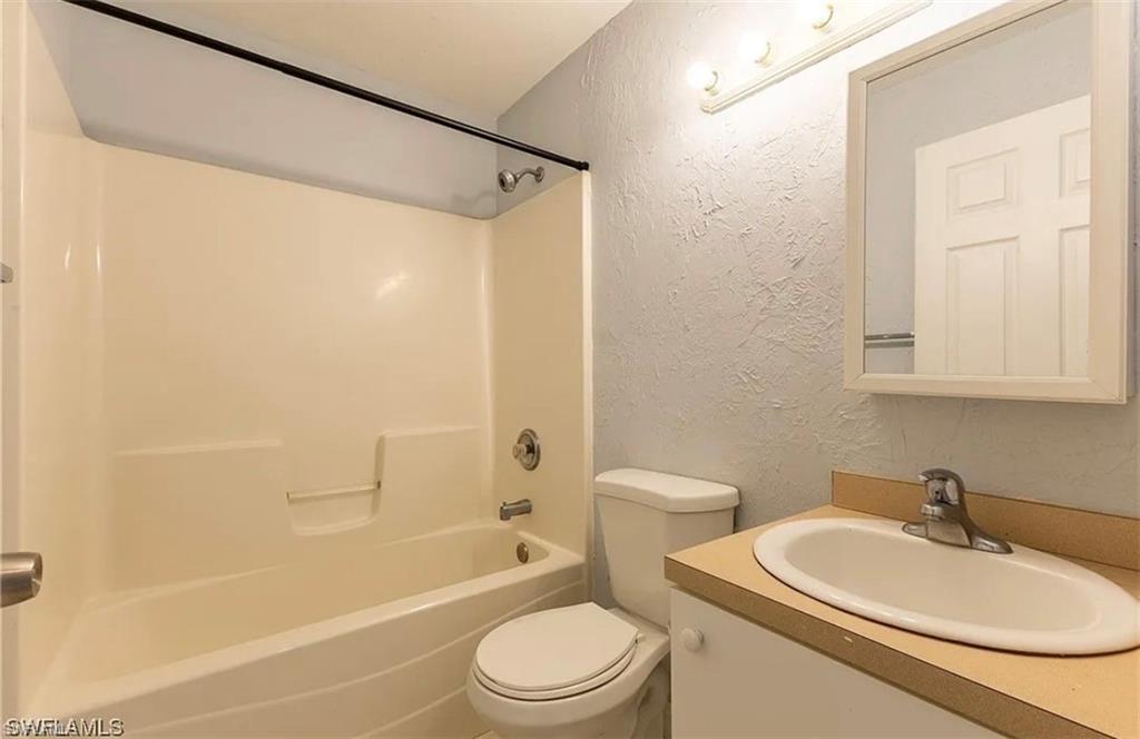 Full bath featuring a textured wall, vanity, and bathing tub / shower combination