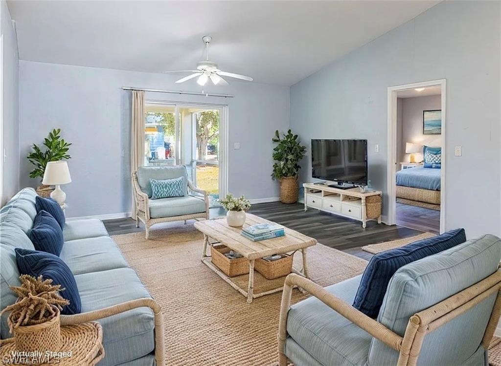Living room with wood finished floors, vaulted ceiling, and a ceiling fan