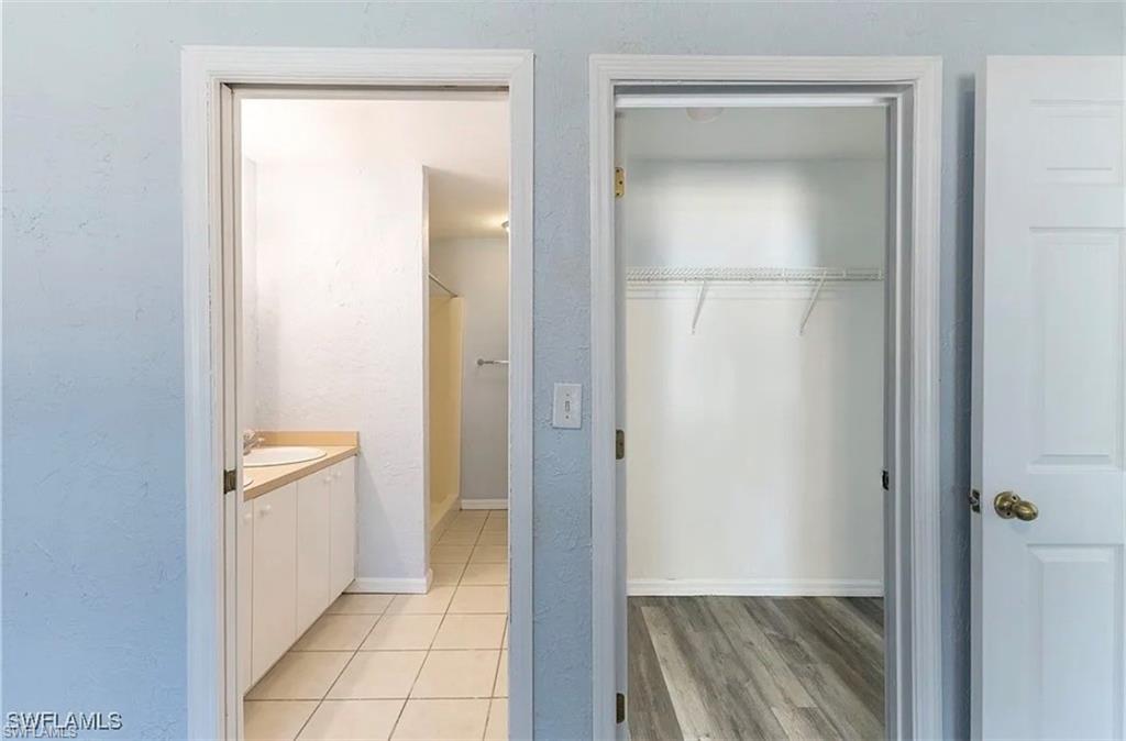 Full bath featuring vanity, a shower, a spacious closet, and light wood-style flooring