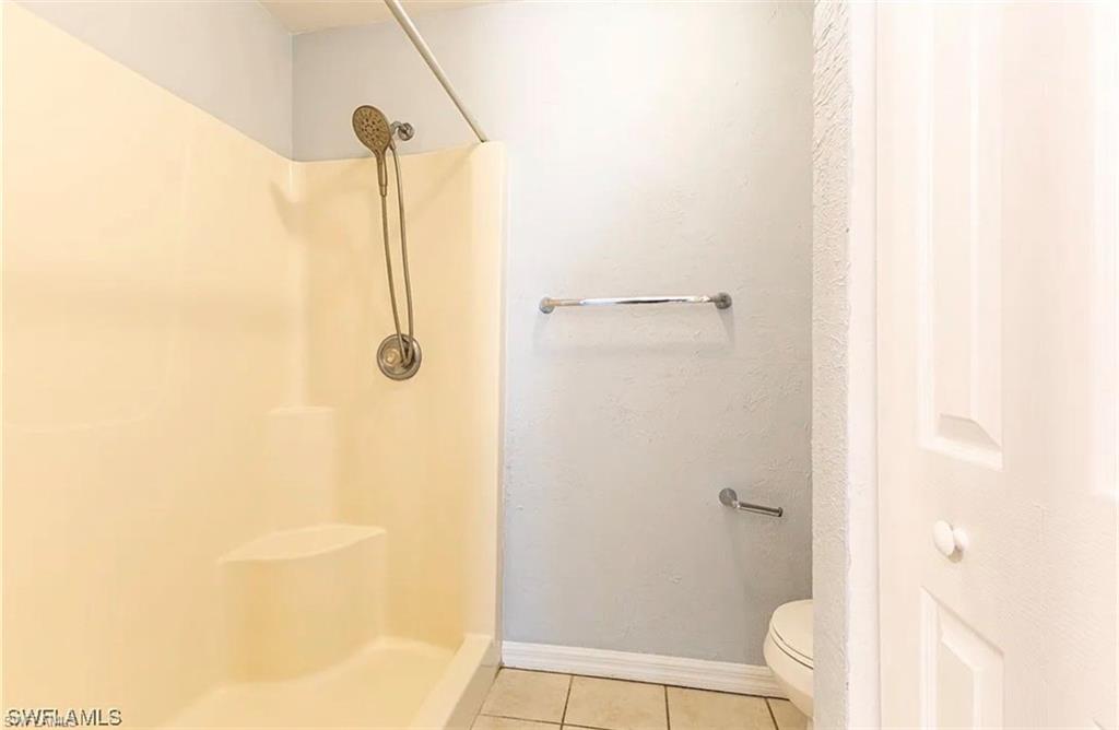 Full bath featuring a stall shower and light tile patterned floors