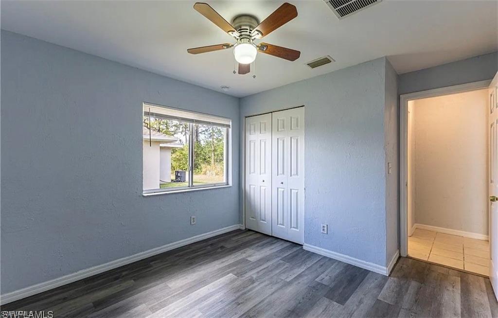 Unfurnished bedroom featuring wood finished floors, a ceiling fan, a closet, and a textured wall