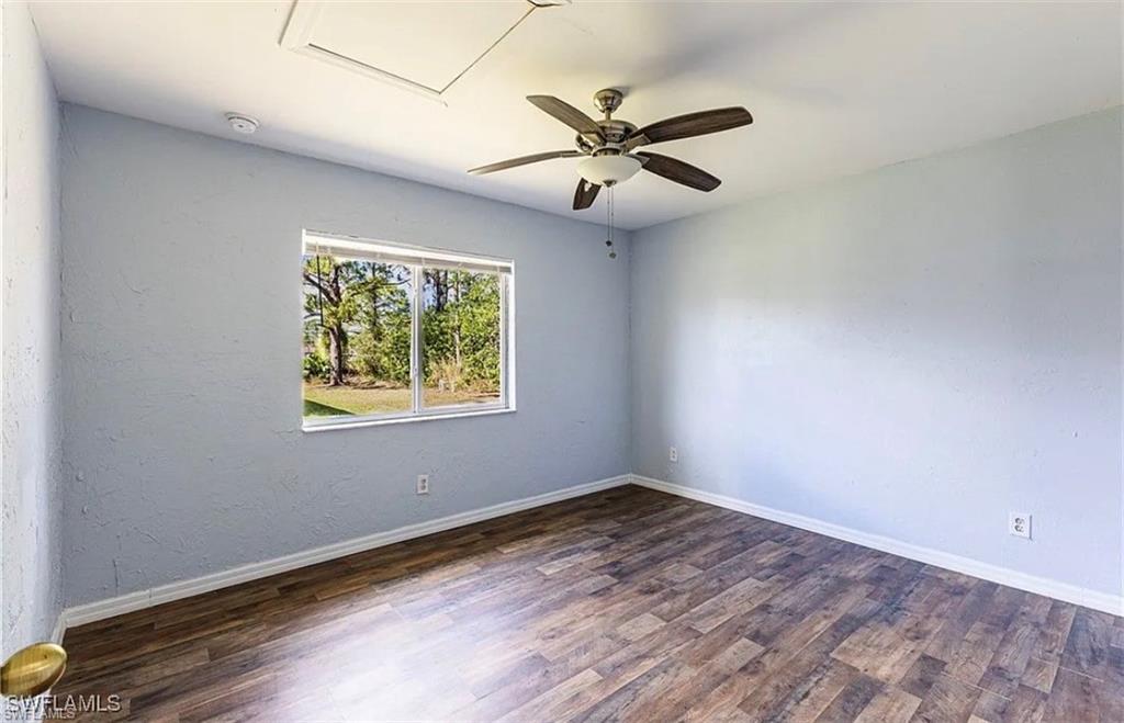 Unfurnished room with a ceiling fan, dark wood-style flooring, and a textured wall