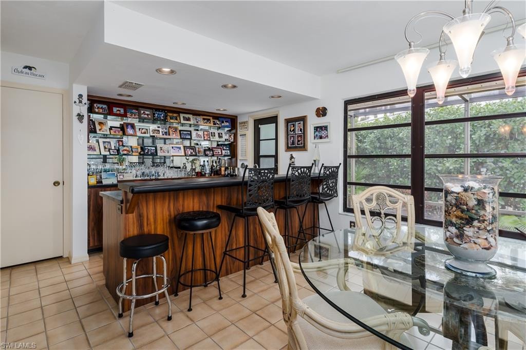 Indoor dry bar with dark countertops, recessed lighting, light tile patterned floors, and open shelves