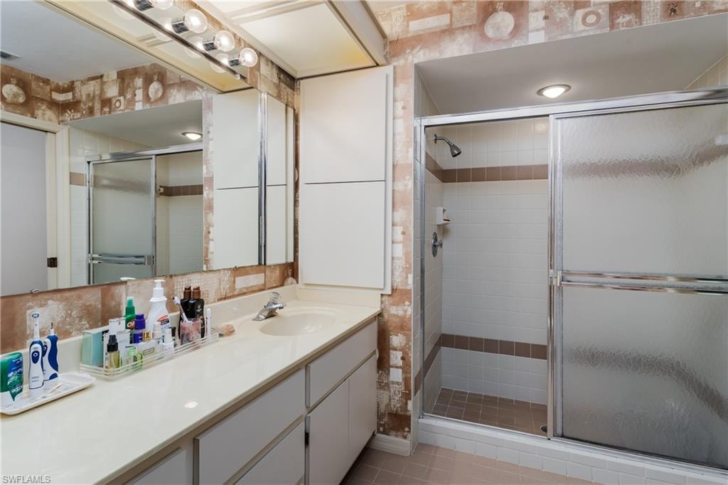 Bathroom featuring vanity, a shower stall, tile walls, and backsplash