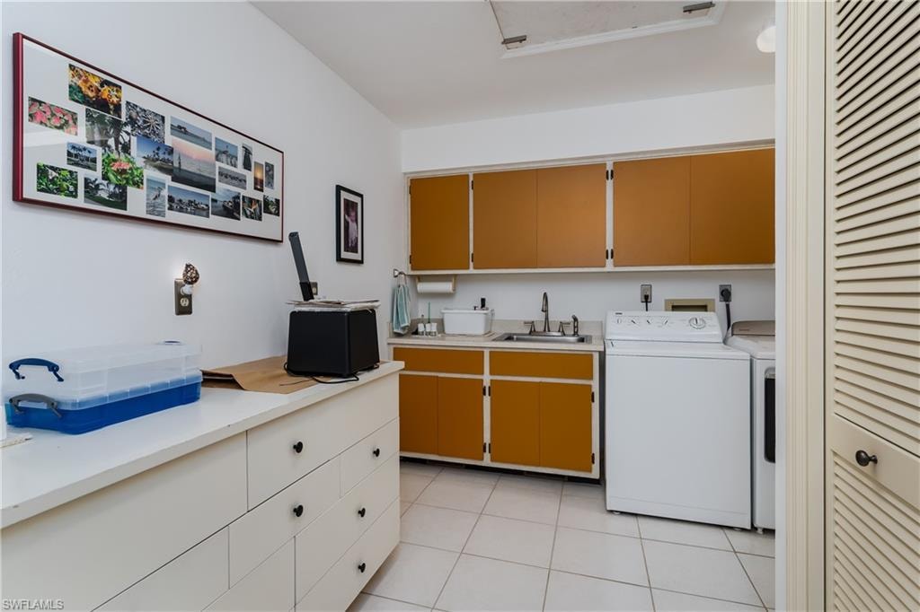 Laundry room featuring cabinet space, washer and dryer, and light tile patterned flooring