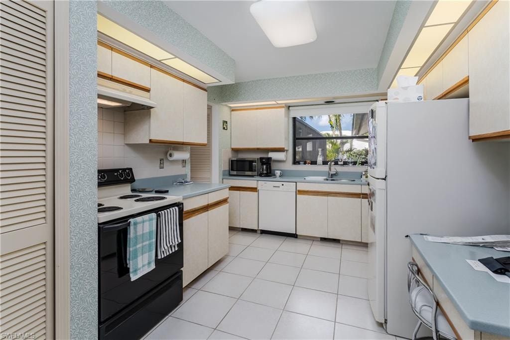 Dual tone kitchen with white appliances, light countertops, two tone color scheme, and light tile patterned flooring