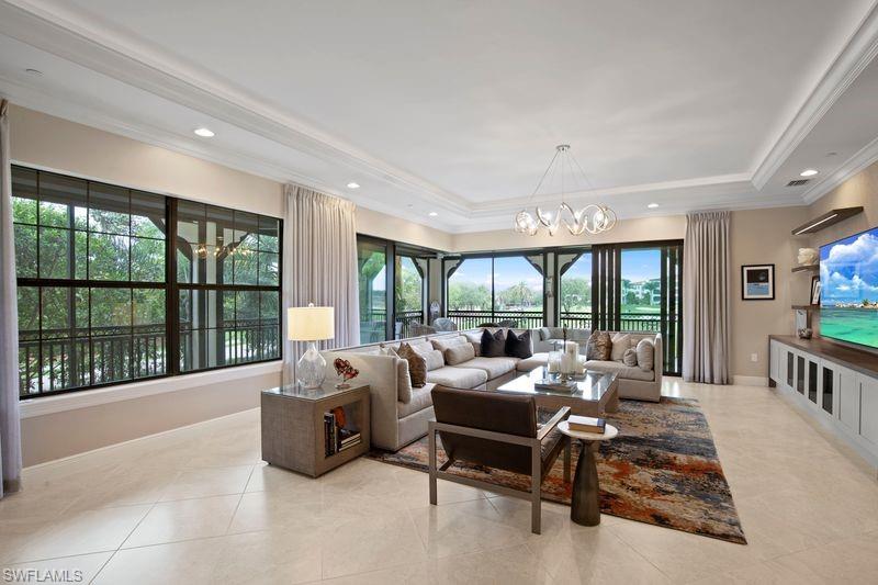 Living room with a chandelier, a tray ceiling, and crown molding