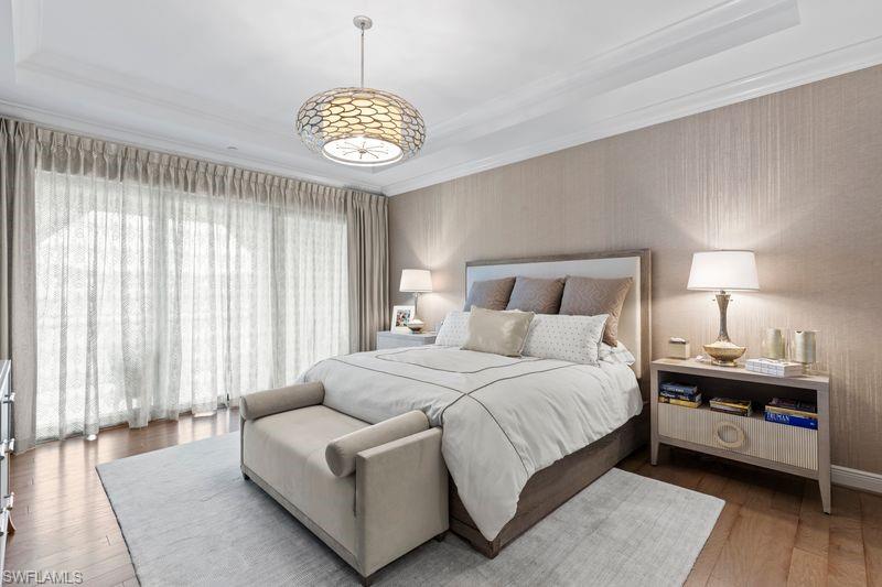 Bedroom featuring hardwood / wood-style floors, a tray ceiling, and ornamental molding